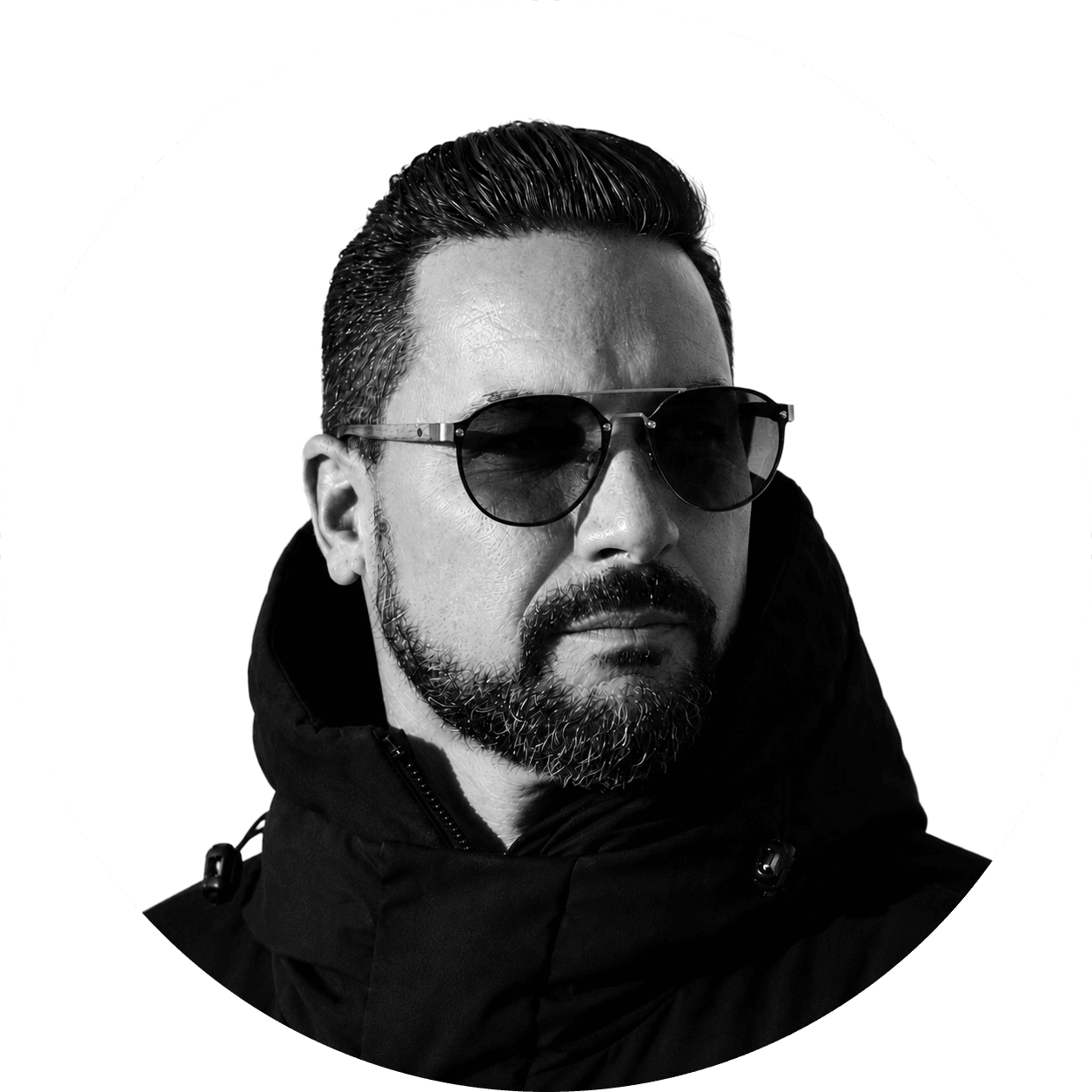 Billy Mason in a black hooded parka and sunglasses, cut out on a white disc.